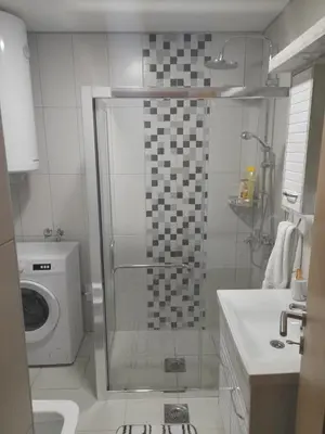 a bathroom with a shower and a washing machine at Holiday apartaments 2 in Niš