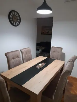 a dining room table with chairs and a clock on the wall at Holiday apartaments 2 in Niš