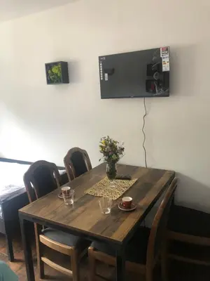 a wooden table with chairs and a television on a wall at Ski sun and fun kopaonik apartmani in Brzeće