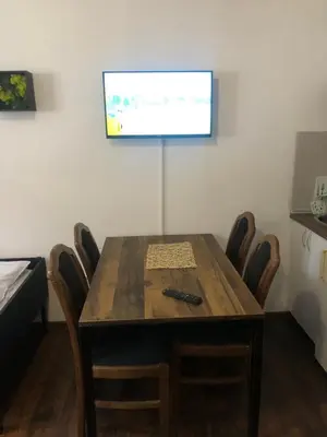 a room with a wooden table with chairs and a screen at Ski sun and fun kopaonik apartmani in Brzeće