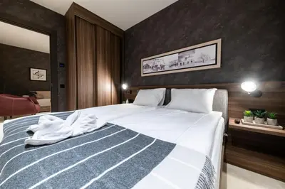 a bedroom with a large bed with white sheets at Woodside Residence 325 in Kopaonik