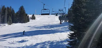 a person riding a ski lift on a snow covered slope at BelinaKop - Kopaonik Centar in Kopaonik
