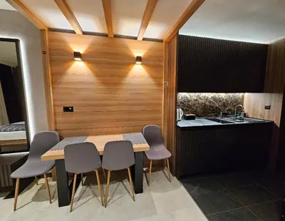 a dining room with a table and chairs and a kitchen at Woodside apartments Kopaonik with garage in Kopaonik
