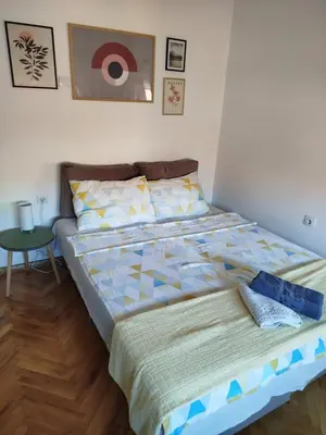 a bedroom with a bed and a table in it at Fina Apartman in Leskovac