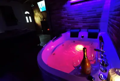 a bathroom with a hot tub with a bottle and wine glasses at Odmaraliste Kod Miće Apartman 3 in Krušar