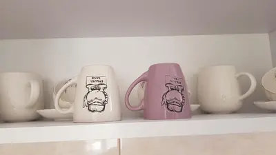 a row of coffee mugs sitting on a shelf at Apartman Provansa in Vrnjačka Banja