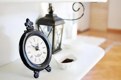 a clock sitting on a table next to a lantern at Apartman Provansa in Vrnjačka Banja
