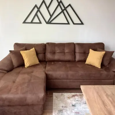 a brown leather couch in a living room with a table at Garnet Star Apartments, Kopaonik, apartman br 2 in Kopaonik