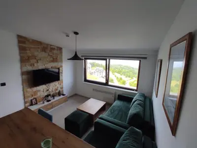 a living room with a green couch and a window at Apartman N98 Milmari Kopaonik in Kopaonik