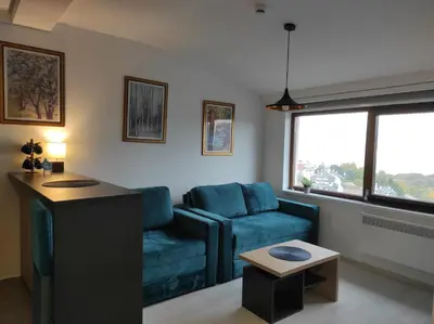 a living room with a blue couch and a table at Apartman N99 Milmari Kopaonik in Kopaonik