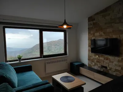 a living room with a couch and a large window at Apartman N99 Milmari Kopaonik in Kopaonik