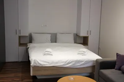 a bedroom with a bed with white sheets and a couch at Aparmani Sorak Kopaonik, Studio Apartman A5 in Kopaonik