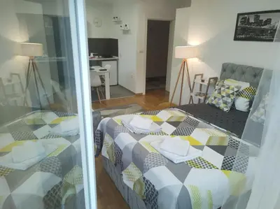 a bedroom with a bed and a living room at Apartman Natura in Vrnjačka Banja