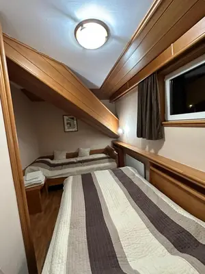 two beds in a small room with a window at Apartman 601 i 603 Kopaonik Centar in Kopaonik