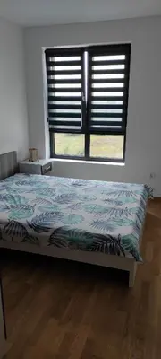 a bedroom with a bed and a window with shutters at LaNe apartman Sokobanja in Soko Banja