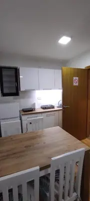 a kitchen with a wooden table and a wooden door at LaNe apartman Sokobanja in Soko Banja