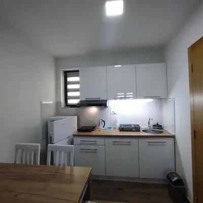a small kitchen with white cabinets and a wooden table at LaNe apartman Sokobanja in Soko Banja