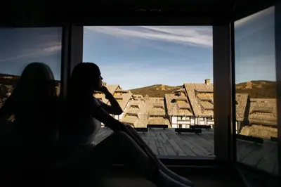a woman sitting in a window talking on a cell phone at Woodside TEA Residences & SPA Kopaonik in Kopaonik