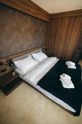 a bedroom with a bed with two towels on it at Woodside TEA Residences & SPA Kopaonik in Kopaonik