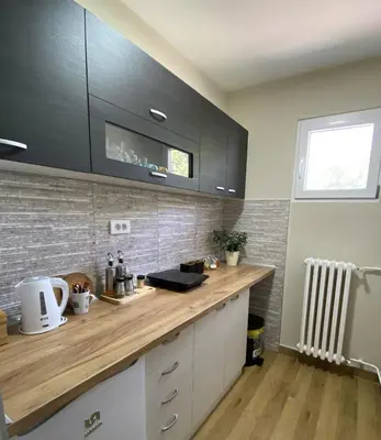 a kitchen with a wooden counter top and black cabinets at Apartman Kosta in Leskovac