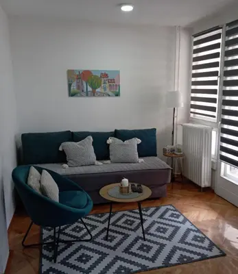 a living room with a blue couch and a table at Apartman Kosta in Leskovac