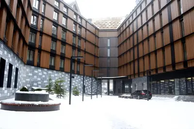 a street in front of a building with snow on the ground at Superior Woodside Residences & Spa Kopaonik in Kopaonik