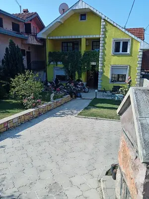 a yellow house with a driveway in front of it at Apartman Zivic in Berilovac