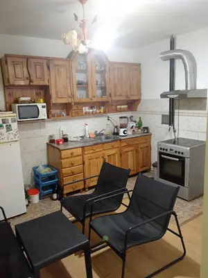 a kitchen with wooden cabinets and a sink and two chairs at Apartman Zivic in Berilovac