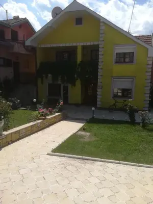 a yellow house with a driveway in front of it at Apartman Zivic in Berilovac