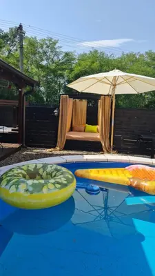 a swimming pool with an umbrella and a surfboard at Odmaraliste Kod Miće Apartman 4 in Krušar