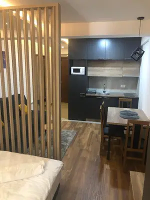 a room with a kitchen and a table and a room with a bed at Kopaonik presidentKop apartman in Kopaonik