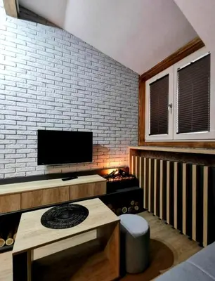 a living room with a tv on a brick wall at VS Apartman , Hotel Župa Kopaonik in Kopaonik