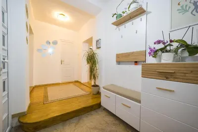 a kitchen with white cabinets and a wooden floor at Petra Guest House in Pirot