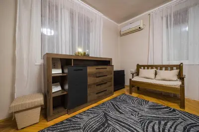 a living room with a bench and a dresser and a window at Petra Guest House in Pirot
