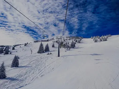 a ski lift on a snow covered slope with trees at Apartman Snezanka Kopaonik in Kopaonik
