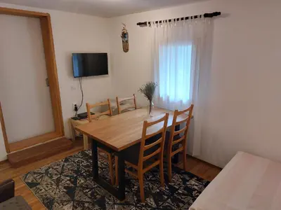 a dining room table with chairs and a television at Udahni prirodu in Raška