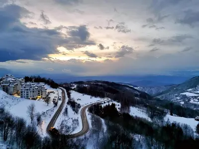 a winding road in the snow at night at NLux 10 Apartment in Kopaonik