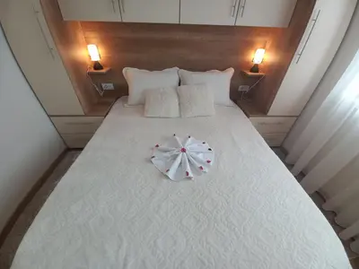 a large white bed with a white umbrella on it at Apartman Marić Raj in Vrnjačka Banja