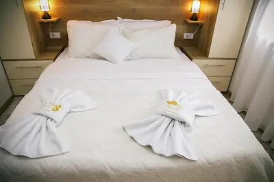 a white bed with white blankets and pillows on it at Apartman Marić Raj in Vrnjačka Banja