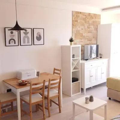 a living room with a table and chairs and a kitchen at Apartman Laura in Kopaonik