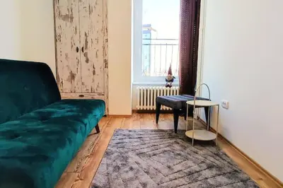 a living room with a green couch and a window at Tizza apartment - Modern flat above the city center in Niš