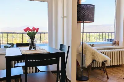 a dining room table with a vase of flowers and a window at Tizza apartment - Modern flat above the city center in Niš