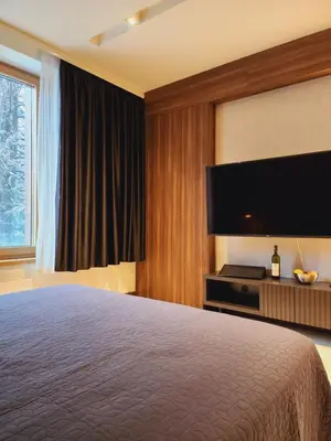 a hotel room with a bed and a flat screen tv at Kopaonik Woodside in Kopaonik