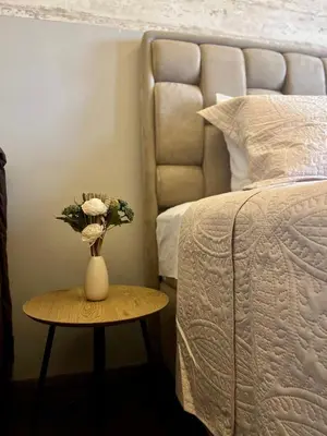 a vase with flowers on a table next to a bed at Apartman K3 Milmari Kopaonik in Kopaonik