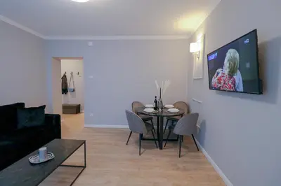 a living room with a table and a tv on a wall at Heart of Niš in Niš