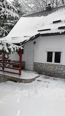 a snow covered house with a fence and a door at Sova Kopaonik in Kopaonik