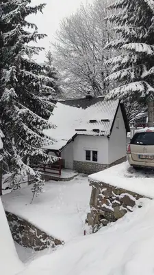 a snow covered house with a car parked in front of it at Sova Kopaonik in Kopaonik