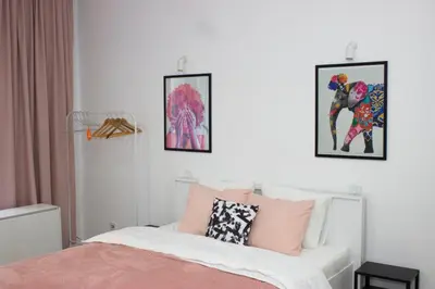 a bedroom with a bed and paintings on the wall at Town Space Apartment Niš in Niš