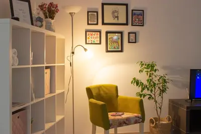 a living room with a green chair and a lamp at Town Space Apartment Niš in Niš