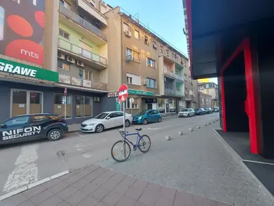 a bike parked on a street next to a stop sign at Town Space Apartment Niš in Niš